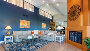 A living room with a beige sofa, a glass coffee table, and a blue patterned rug. There are two side tables with lamps and decorative items. - Hacienda-Resort Style-Golf, Music, & Art Paradise in La Quinta, PGA West Stadium (La Quinta)