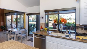 A modern kitchen with a built-in dishwasher, a granite countertop, and a window with a view of the outdoors. - Hacienda-Resort Style-Golf, Music, & Art Paradise in La Quinta, PGA West Stadium (La Quinta)