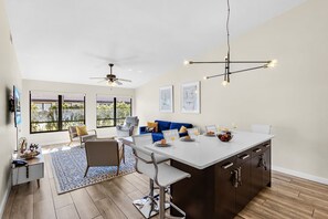 A modern kitchen with a central island, dining area, and seating. - Renovated Sarasota Retreat Near Beaches, Pool & Tennis - Spanish Pine Villa #210 - Roelens (Sarasota)