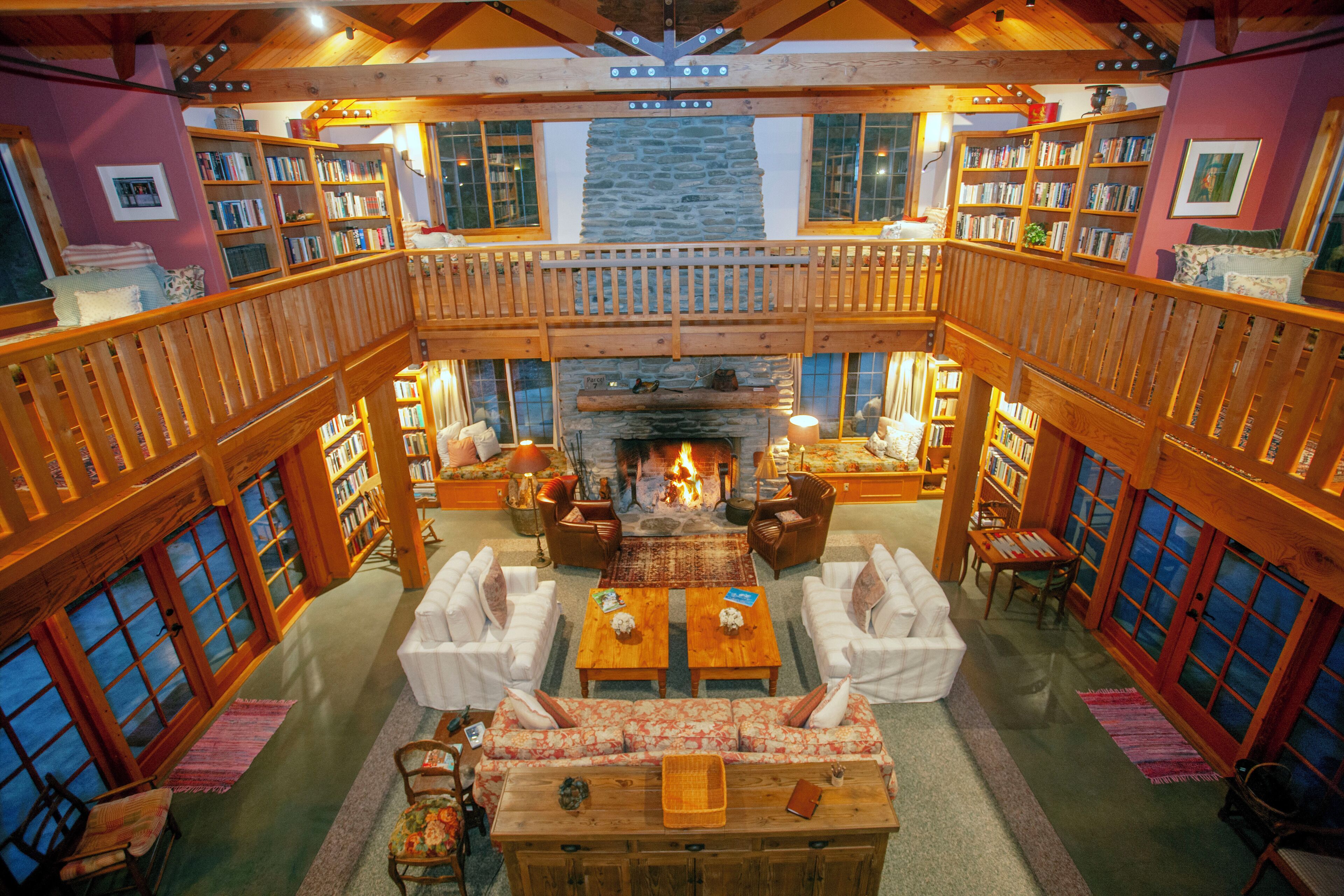 A spacious library with a central fireplace, multiple bookshelves, and comfortable seating areas.