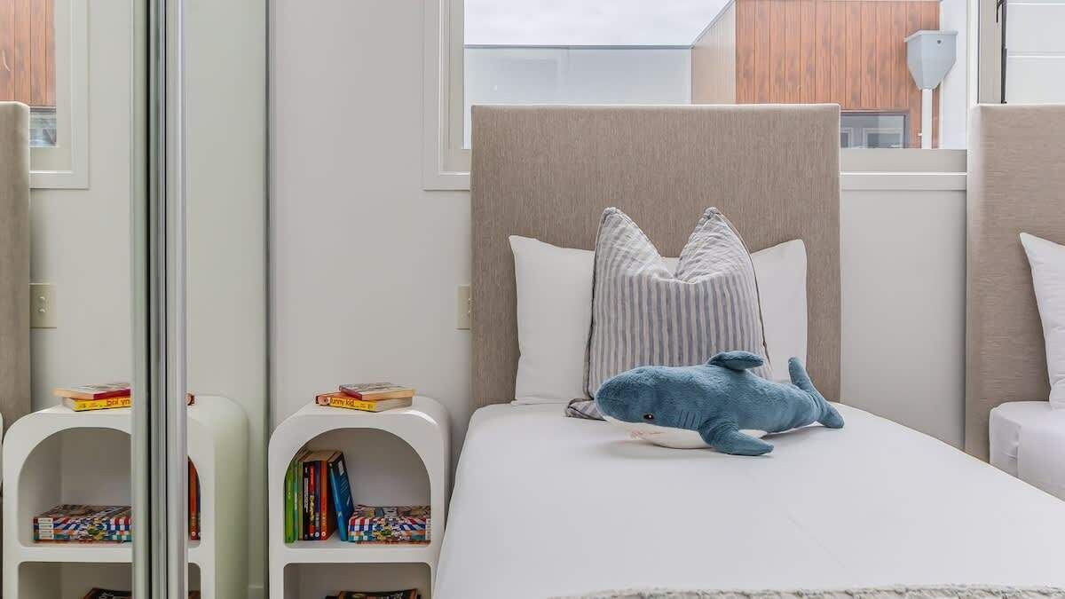 A bedroom with a bed, pillows, a stuffed toy, and bookshelves.