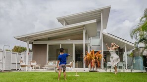 A modern house with a covered patio, outdoor seating, and a well-maintained lawn. - Daybreak Shores (Casuarina)