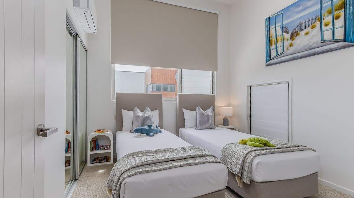 Habitación de hotel con dos camas, una ventana, un cuadro y una puerta.