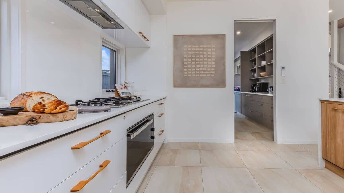 Una cocina moderna con estufa a gas, horno y pomos de madera en los armarios.