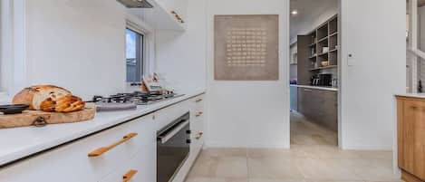 A modern kitchen with a gas stove, oven, and wooden handles on the cabinets.