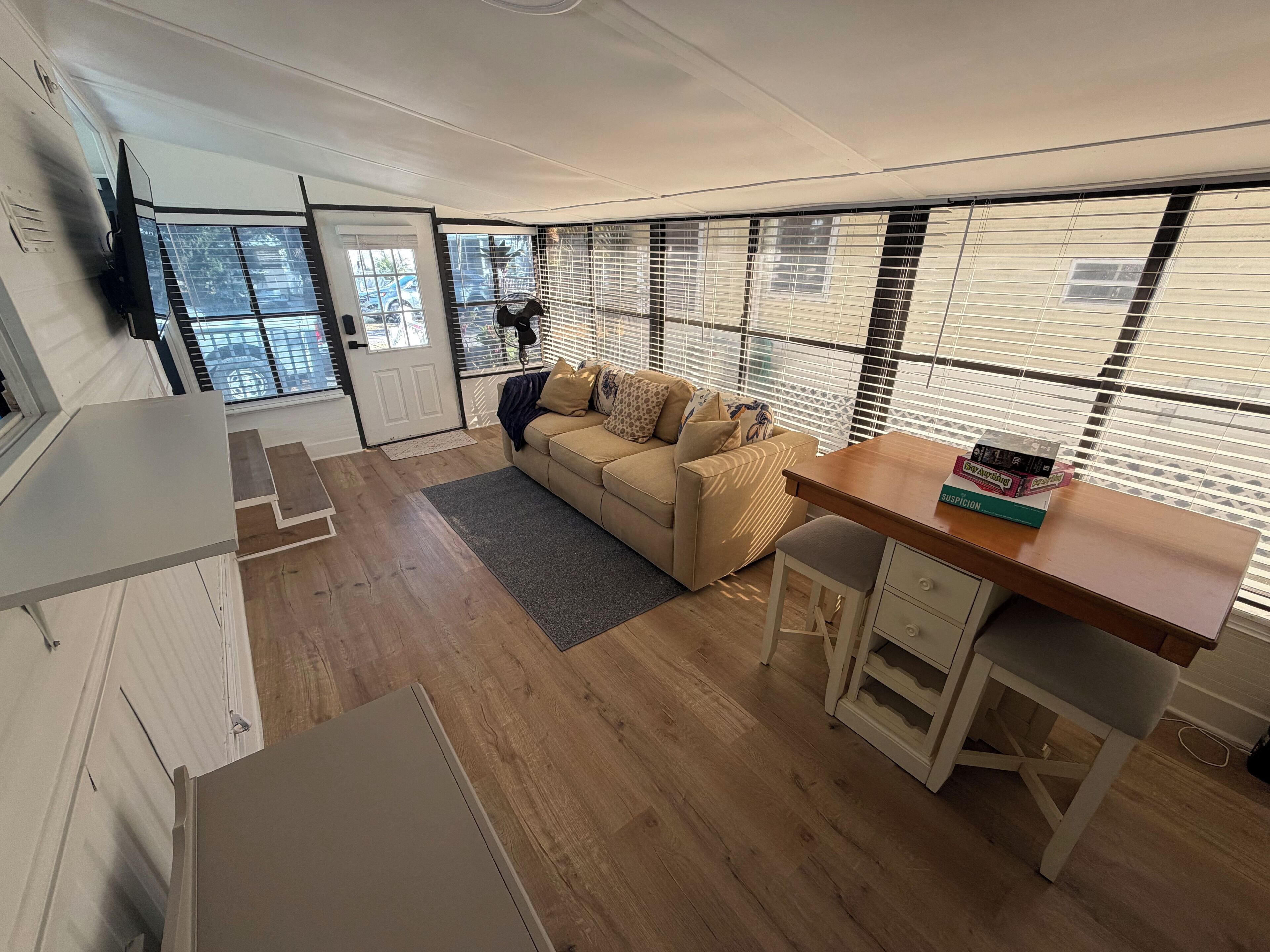 A modern living room with a sofa, a wooden table, and a TV mounted on the wall.