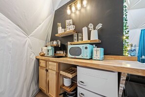 A compact kitchen with a microwave, toaster, and small refrigerator. There are wooden cabinets and a countertop with various kitchen items. - Luxury Glamping Dome 6 miles from Downtown Gatlinburg with all the amenities (Pigeon Forge)