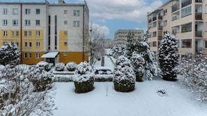 Ein Wohngebiet mit mehrstöckigen Mehrfamilienhäusern, schneebedeckten Bäumen und einem Auto auf der Einfahrt.