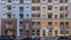En flereetagers boligbygning med altaner, en murstensfacade og et skilt, der angiver en butik i stueetagen.