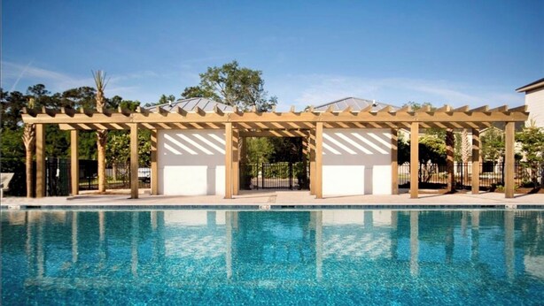 Una piscina con una estructura de pérgola de madera.
