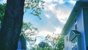 Een huis met een witte schutting, een grote boom en een heldere blauwe lucht.