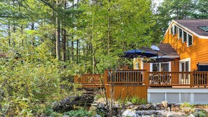 Une cabane dotée d’une terrasse, entourée d’une forêt.