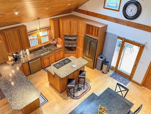 Une cuisine spacieuse dotée de meubles en bois, de plans de travail en granit, d’appareils électroménagers en acier inoxydable et d’un grand îlot central avec des tabourets de bar.