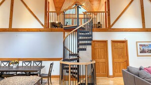 Un intérieur spacieux agrémenté d’un escalier en colimaçon central, de poutres en bois et d’un lustre.