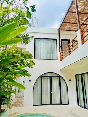 A two-story building with a pool, large windows, and a balcony. - Casa Myla by Betterplace (Pecatu)