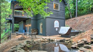 A two-story house with a deck, outdoor seating, and a small pond. - Twin Timbers at the Falls | 2 Luxury Homes, Exclusive Pool, 13BR Retreat (Fairview)