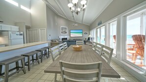 Een ruime eetruimte met een lange tafel, banken en een kroonluchter.