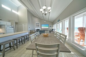 A spacious dining area with a long table, benches, and a chandelier. - Ocean Front 3 bed 3 bath sleeps 12 & Pet Friendly (Panama City Beach)