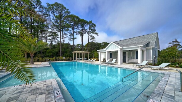 Ein Swimmingpool mit Liegestühlen und einer überdachten Terrasse.