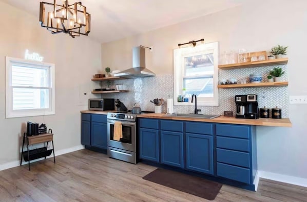 A modern kitchen with blue cabinets, a stainless steel range, and a built-in microwave.