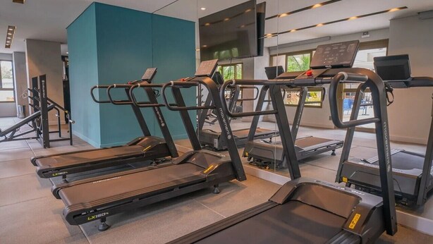 A gym with multiple treadmills, exercise equipment, and a large screen TV. - Studio next to Giovanni Metro Station | Vibra | Morumbi Stadium (São Paulo)