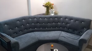 Un canapé d’angle bleu foncé, à l’aspect capitonné et doté d’une forme incurvée, placé dans un coin de la pièce.