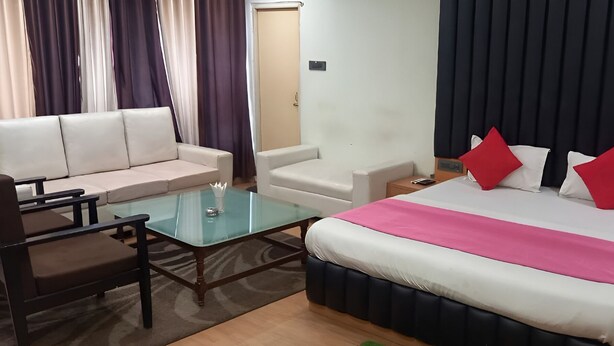 Une chambre d’hôtel avec un lit, un canapé, une table basse en verre et une table de chevet.