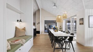 A modern interior with a long dining table, black chairs, a bench with cushions, and pendant lights. - VillaVilla 916 - Skåstrup Strand, Fyn og øer (Bogense)