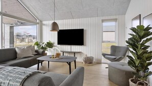 A modern living room with a sofa, armchair, coffee table, and a TV mounted on the wall. - VillaVilla 916 - Skåstrup Strand, Fyn og øer (Bogense)