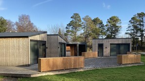 A modern outdoor building with wooden deck and glass doors, surrounded by trees. - VillaVilla 924 - Marielyst, Lolland/Falster/møn (Væggerløse)