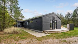 A modern, dark-colored building with a sloped roof, large windows, and a small deck area. - VillaVilla 944 - Blokhus, Nordjylland (Blokhus)