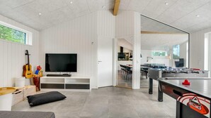A modern living room with a flat-screen TV, a guitar, and a foosball table. - VillaVilla 944 - Blokhus, Nordjylland (Blokhus)