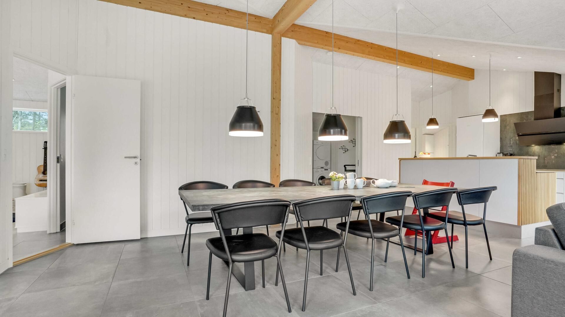Et moderne køkken med træloft, spiseplads med et marmorbord og sorte stole.