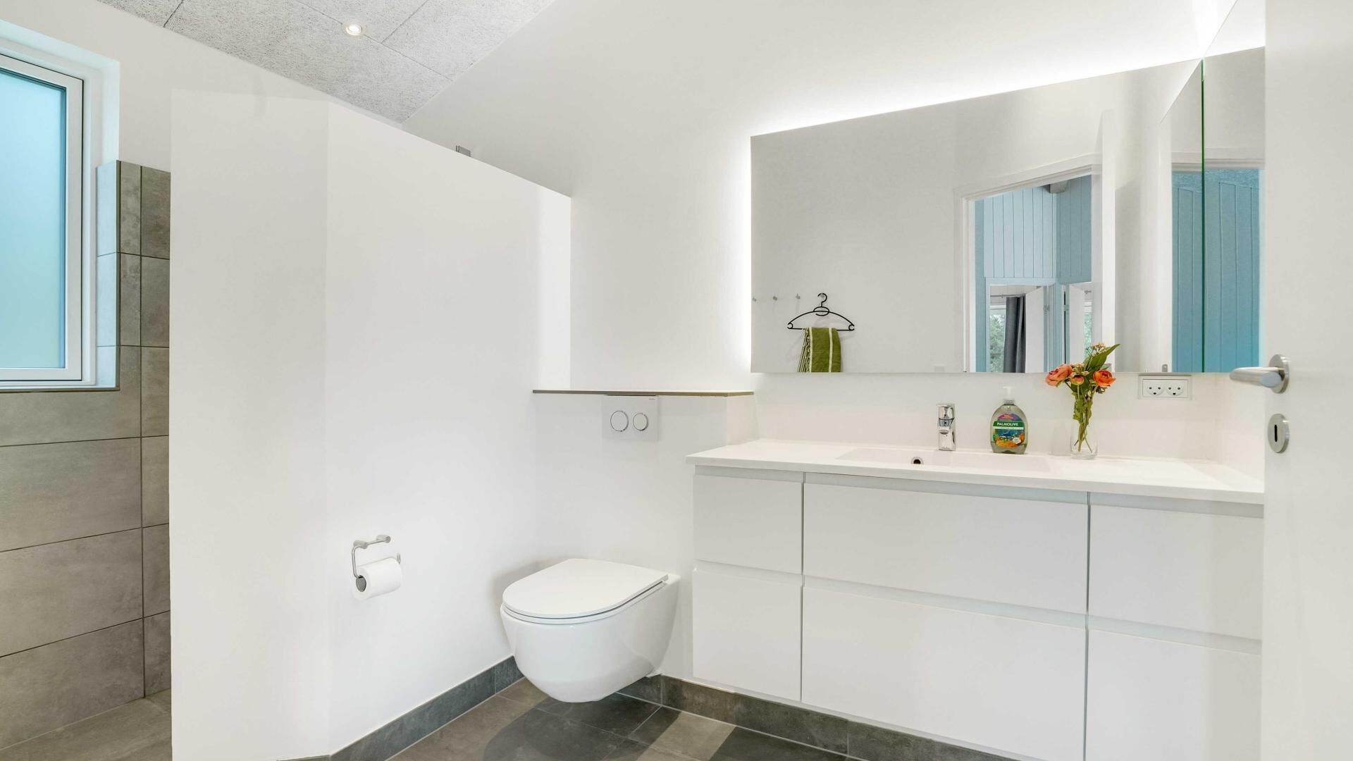 Un baño moderno con inodoro, lavabo con espejo y barra para toallas.