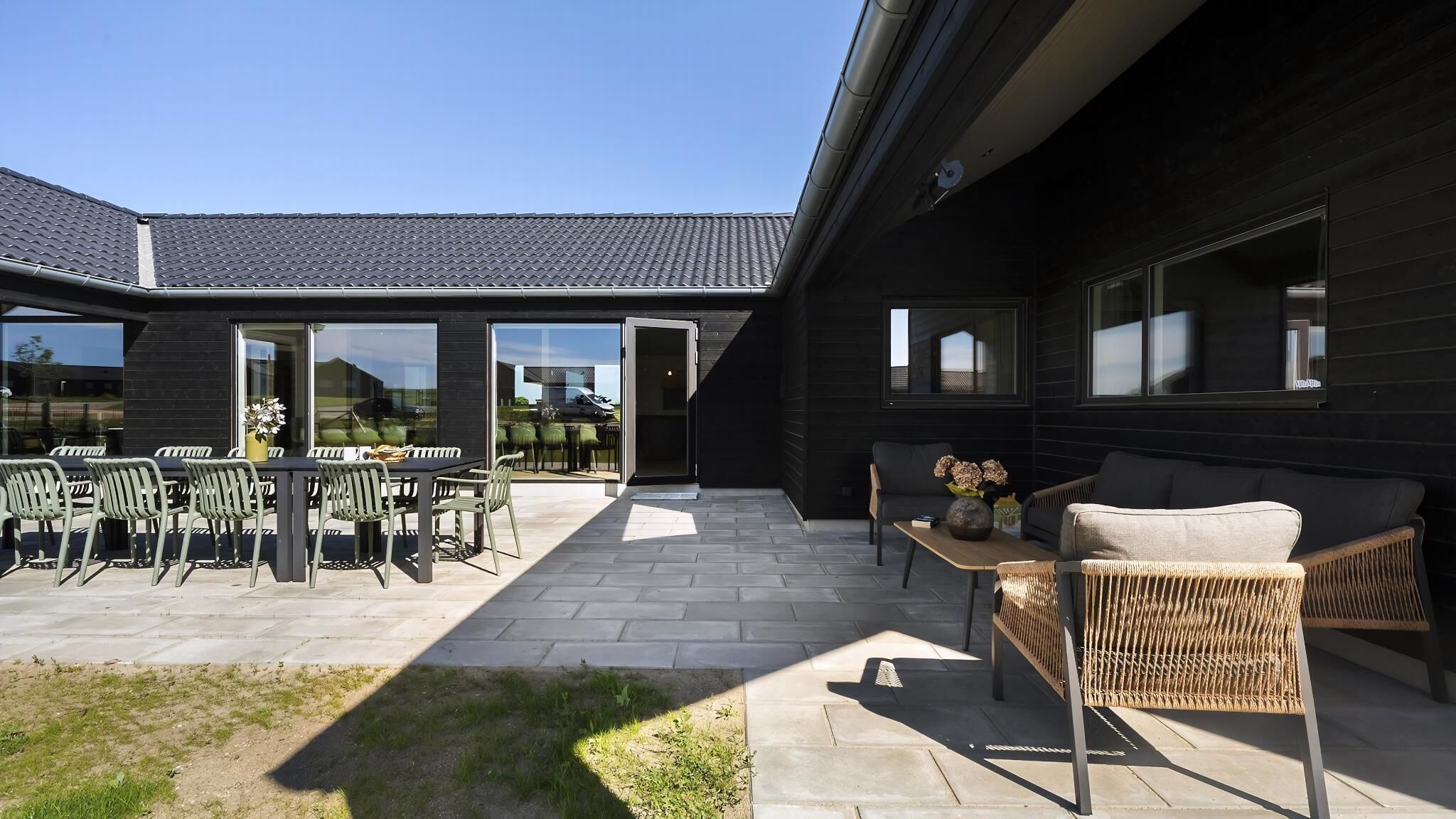 Een modern terras buiten met een eethoek, zitplaatsen en uitzicht op het omliggende landschap.