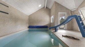 Ein Schwimmbecken mit einer blauen Rutsche, einer Leiter und einem Fenster mit Blick.