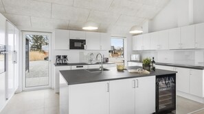 Una cocina moderna con armarios blancos, una isla central con un lavamanos y un horno empotrado.