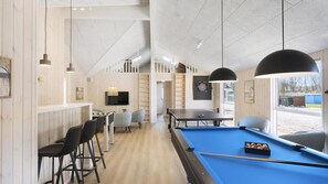 A pool table with a blue felt surface, a dartboard, and a bar area with stools and a television. - VillaVilla 933 - Østersøbadet, Lolland/Falster/Møn (Rødby)