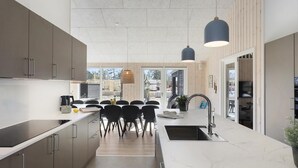 A modern kitchen with a central island, a dining area with chairs, and a view of the outdoors. - VillaVilla 933 - Østersøbadet, Lolland/Falster/Møn (Rødby)