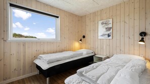 Ein Zimmer mit zwei Betten, einem Fenster und einer Wandleuchte.