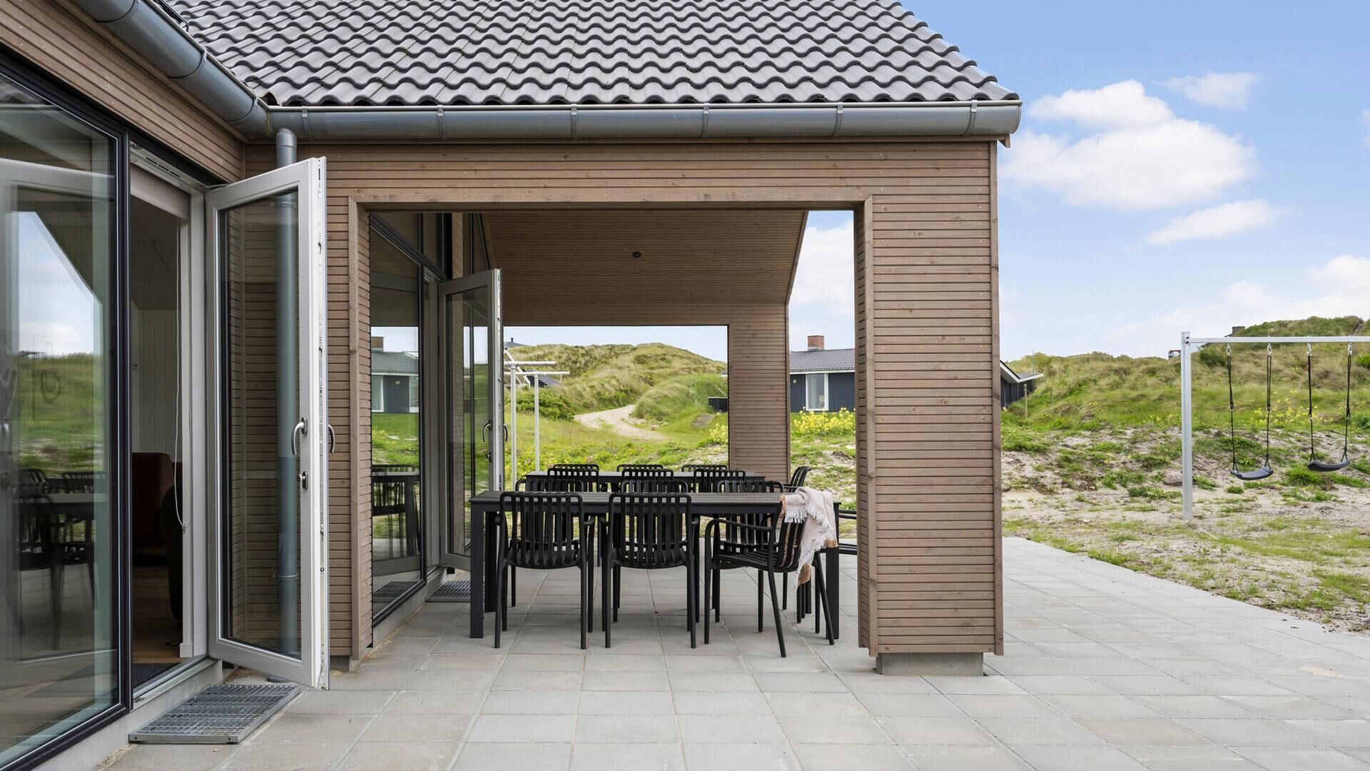 Un espace extérieur abrité, avec une table et des chaises, une pergola en bois et une vue sur le paysage.