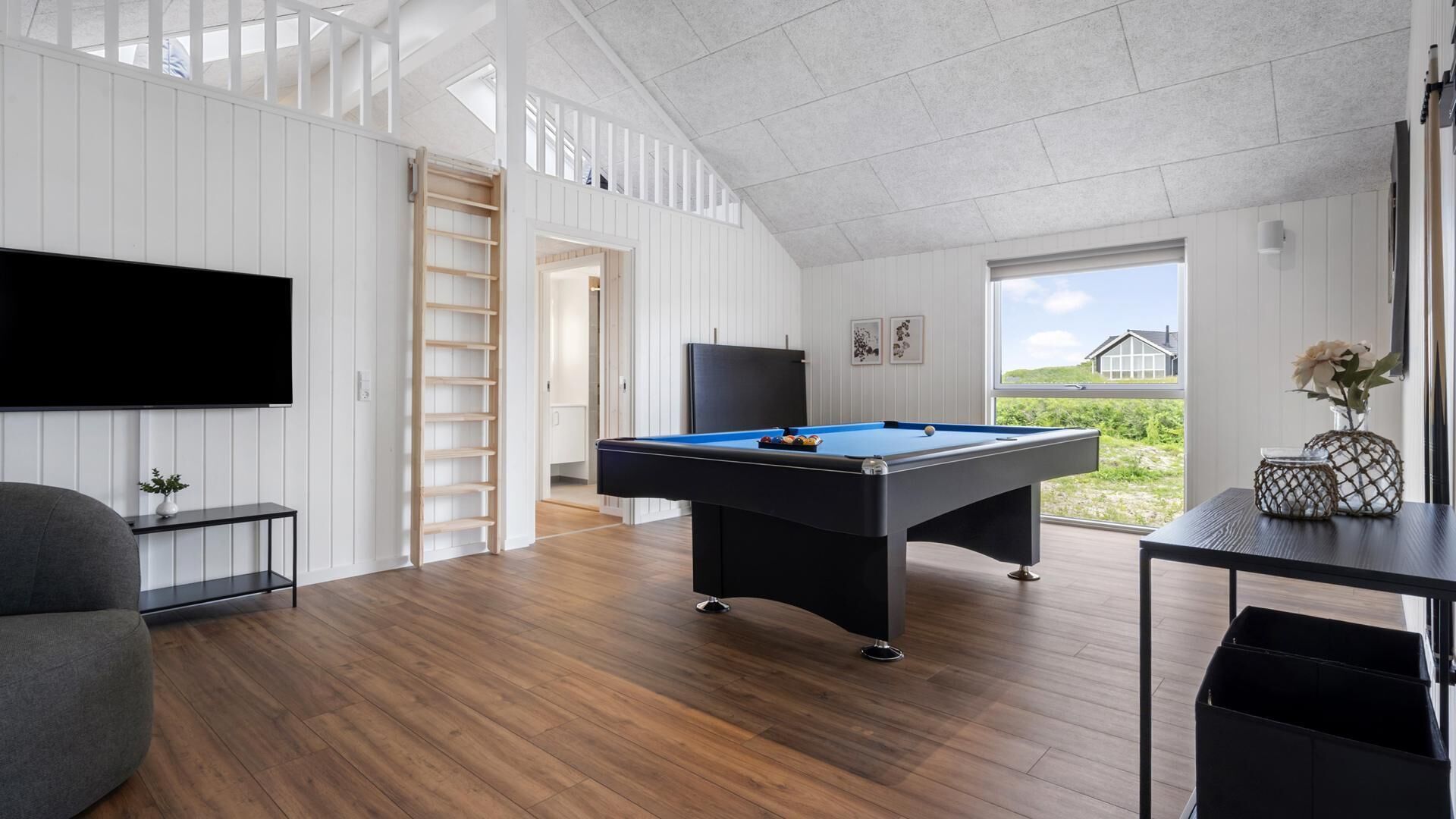 A modern room with a pool table, a flat-screen TV, and a view of the outdoors.