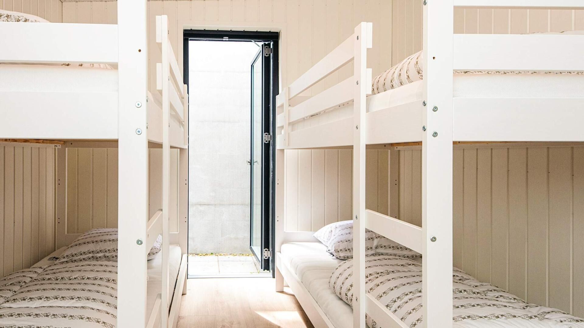 Habitación con literas y una puerta que da a un pasillo.