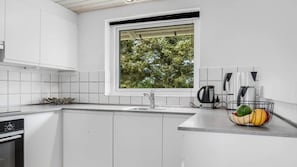 A modern kitchen with white cabinetry, a stainless steel sink, a kettle, and a fruit bowl on the counter. - VillaVilla 937 - Vrist, Vestjylland (Harboøre)