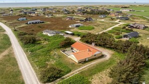 Oversigtsbillede af et boligområde med huse, veje og et vandområde i baggrunden.