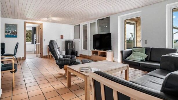 En moderne stue med sofa, lænestol, sofabord og fjernsyn.