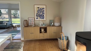 Un meuble en bois agrémenté d’objets décoratifs, une œuvre d’art encadrée et un panier en osier.
