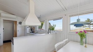 Una cocina moderna con armarios blancos, una isla grande y vistas a través de las ventanas.