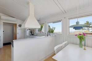 Eine moderne Küche mit weißen Schränken, einer großen Kochinsel und Blick durch die Fenster.