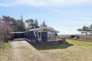 Ein modernes Haus mit überdachter Veranda, befestigter Auffahrt und Rasenfläche.